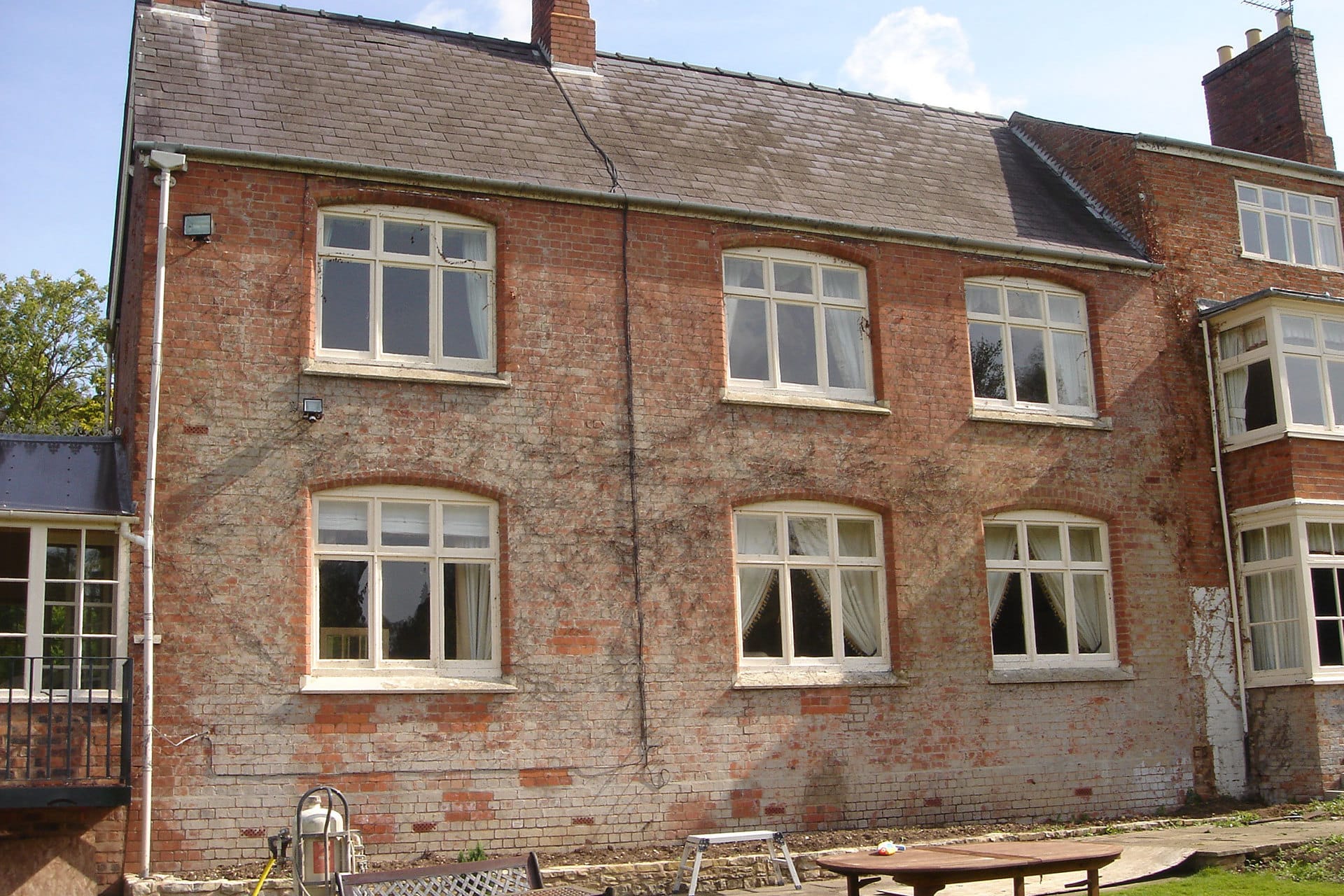 'Before' Image of a Building, showing ivy remnants and faded paint on the brickwork.