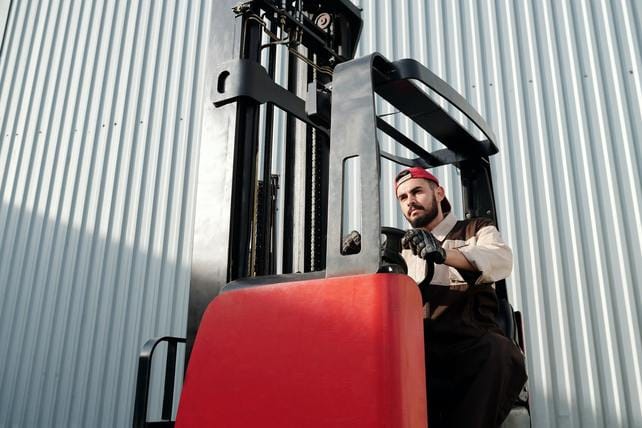 Man on a forklift truck next to a cladding covered building to illustrate warehouse cleaning and cladding cleaning services offered by Encanto.