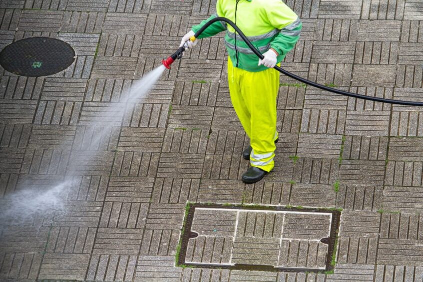 Encanto operative cleaning a commercial pavement with a pressure washer